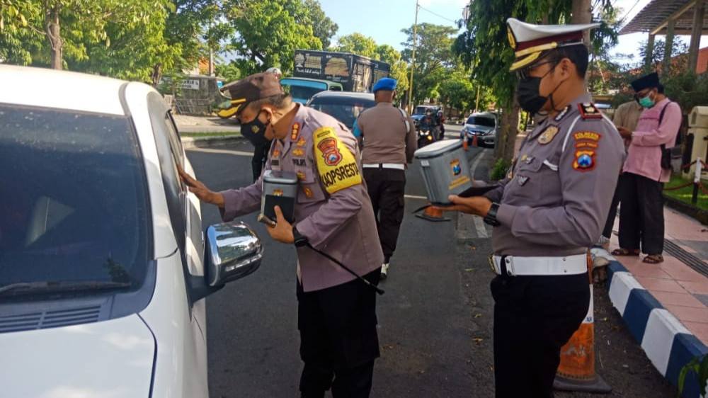 Kapolresta Banyuwangi Kombespol Arman Asmara Syarifuddin menyerahkan tempat sampah dan masker pada pengendara mobil. (Foto: Muh Hujaini/Ngopibareng.id)