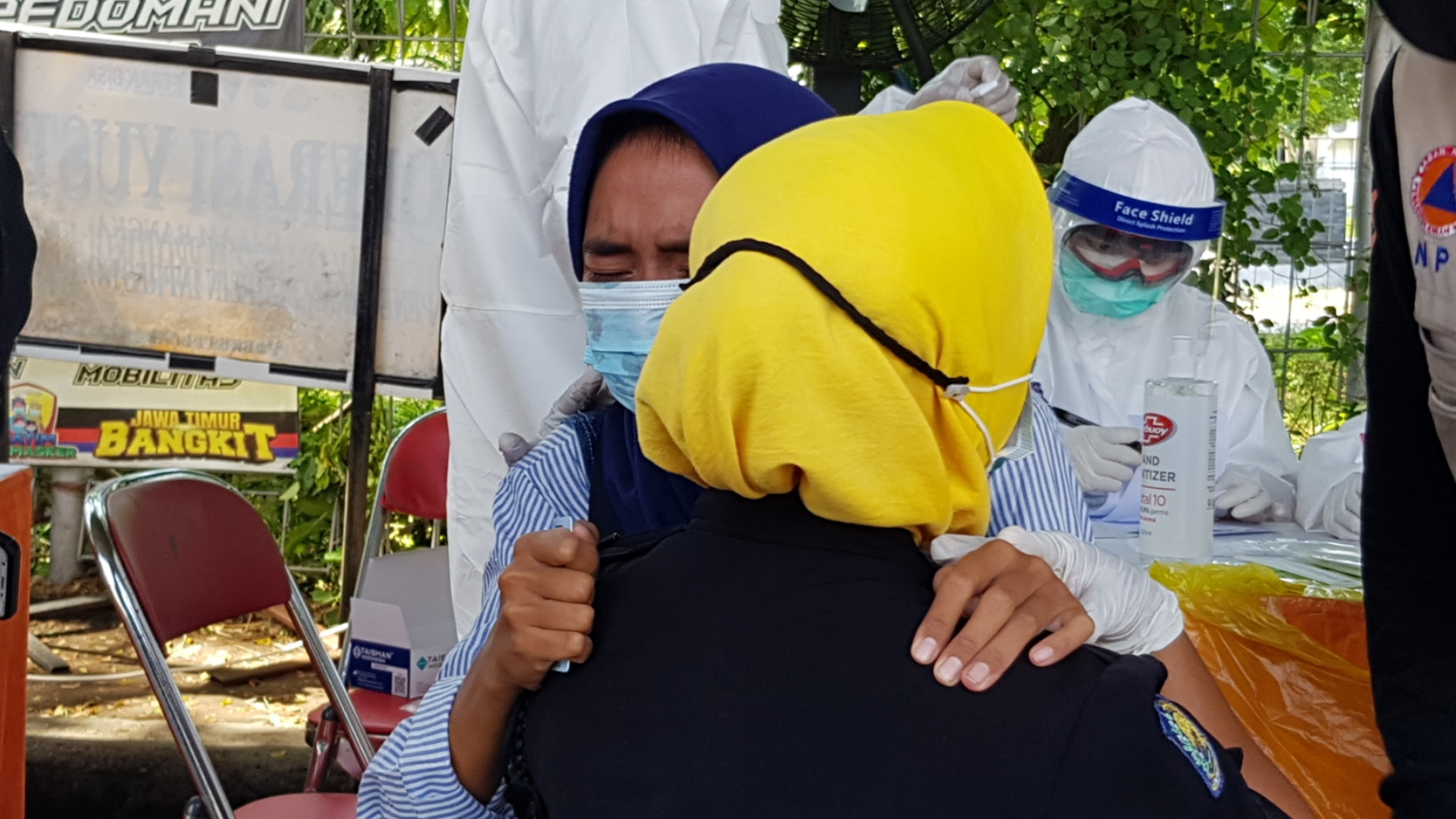 Novi pengendara asal Bangkalan menangis dipelukan petugas Linmas Surabaya ketika hendal mengikuti swab tes di Posko Penyekatan Suramadu, Surabaya, Kamis 10 Juni 2021. (Foto: Fariz Yarbo/Ngopibareng.id)