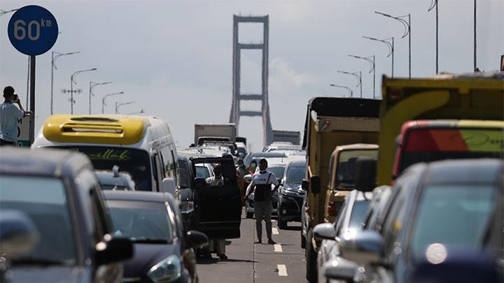 ejumlah warga dari Pulau Madura keluar dari mobilnya saat mengantre masuk ke Surabaya di akses keluar Jembatan Suramadu, Surabaya, Ahad, 6 Juni 2021. Petugas gabungan melakukan penyekatan di jembatan penghubung Surabaya dan Madura. (Foto: Antara/Didik Suhartono)