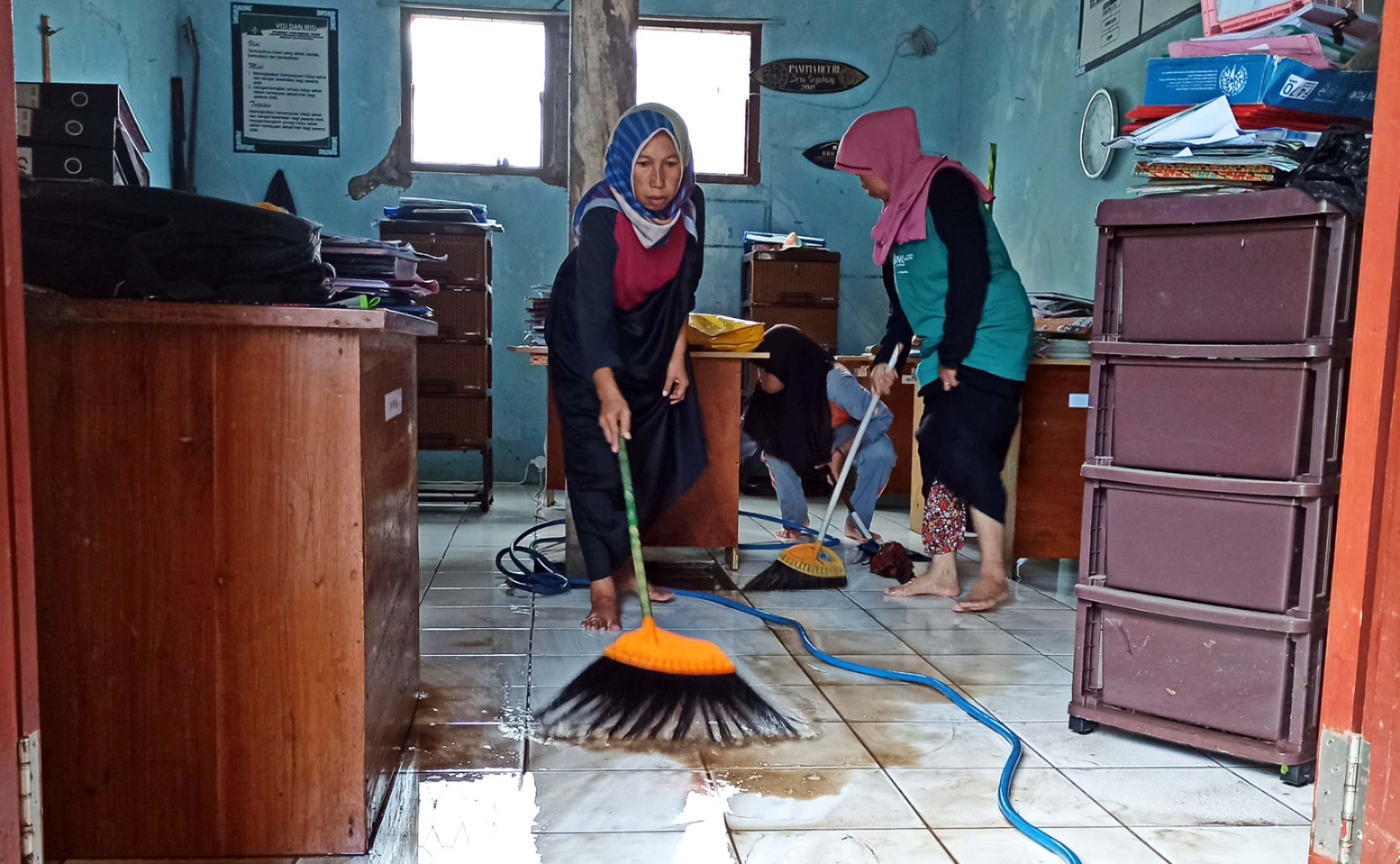 Guru dan murid MTs Nahdlatuth Thullab membersihkan sisa air dan lumpur di salah satu ruangan sekolah (Foto: Muh Hujaini/Ngopibareng.id)