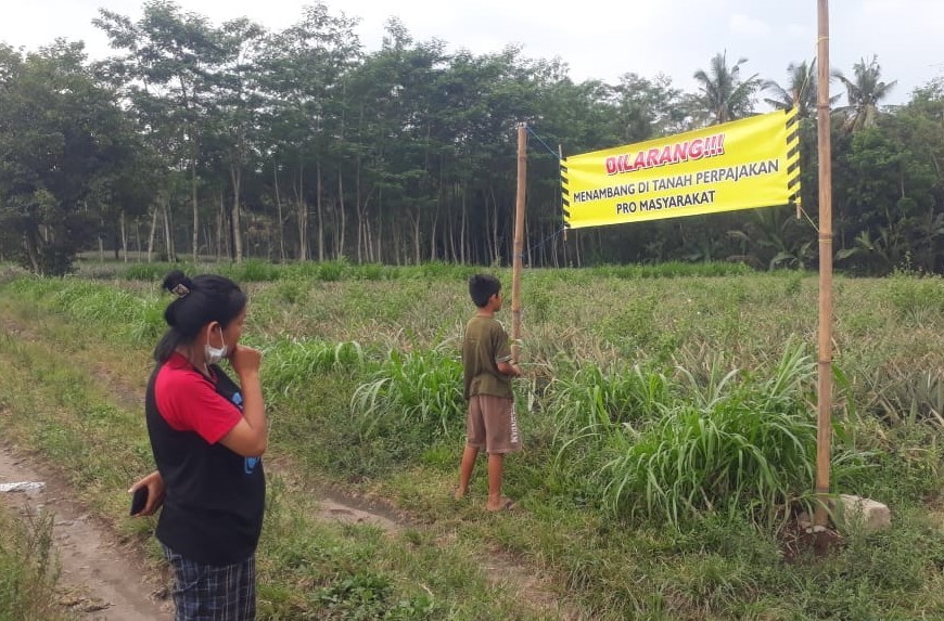 Warga memasang spanduk yang berisi larangan penambangan pasir di tanah yasan atau perpajakan di Blitar. (Foto: Choirul Anam/Ngopibareng.id)