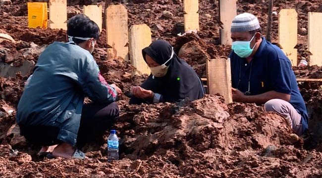 Keluarga berdoa di makam Puji Apriani yang meninggal bersama bayi di kandungannya. (Foto: Fakhrur Rozi/Al Jazeera)