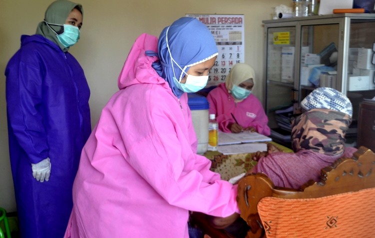 Petugas Puskemas Tegalampel Bondowoso menyuntikkan vaksin Covid-19 kepada seorang warga. (Foto: Guido Saphan/Ngopibareng.id)