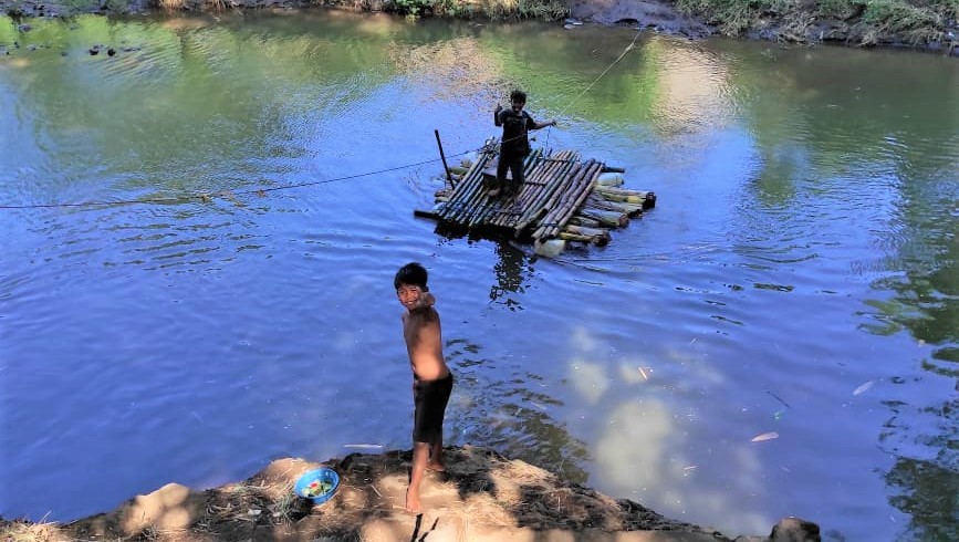 Warga di Kelurahan Kedungasem, Kota Probolinggo naik rakit batang pisang untuk menyeberangi sungai sejak jembatan darurat amblas diterjang banjir. (Foto: Ikhsan Mahmudi/Ngopibareng.id)