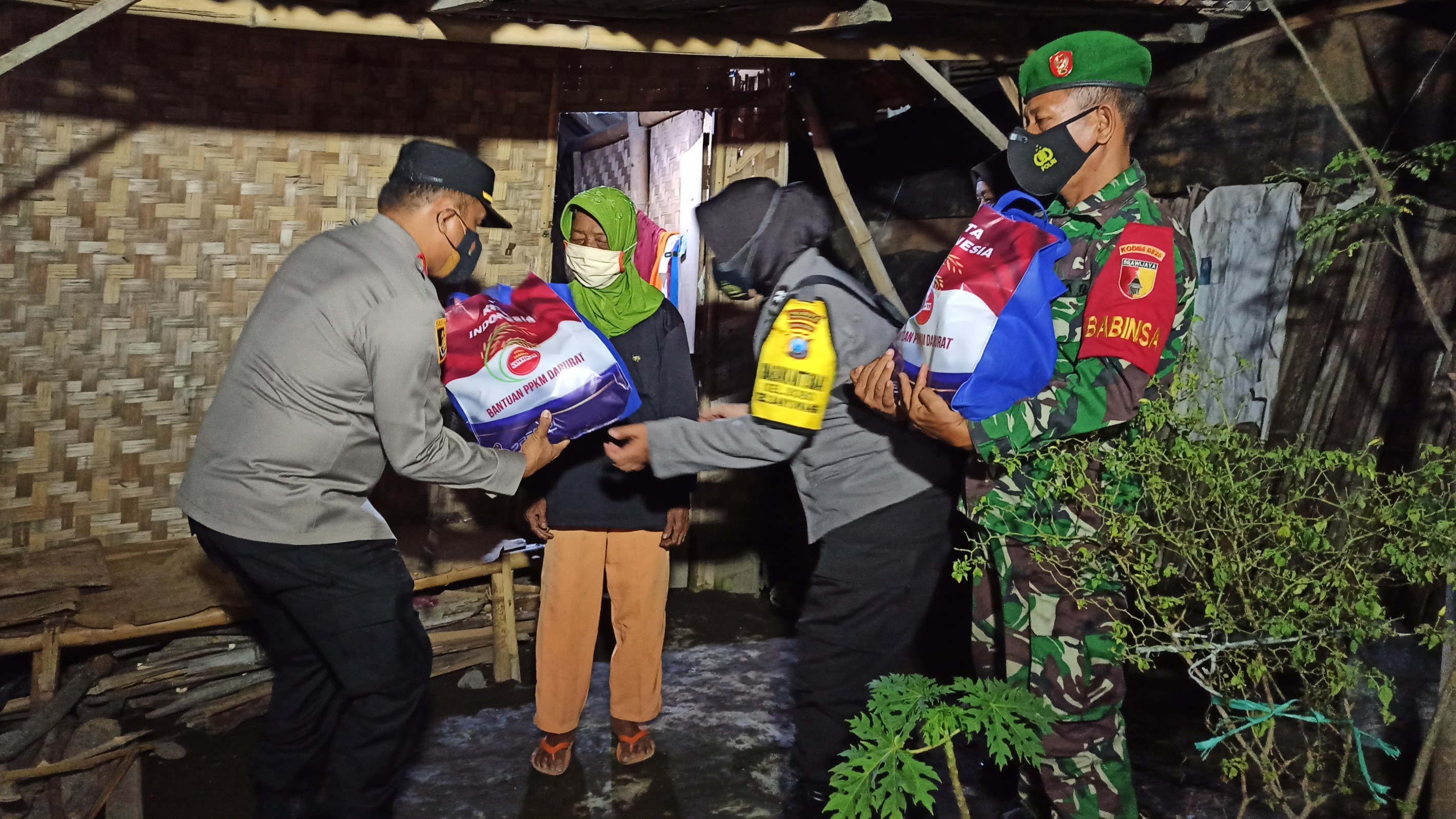 Kapolresta Banyuwangi AKBP Nasrun Pasaribu beserta personil TNi menyerahkan sembako kepada warga tidak mampu (foto:Muh Hujaini/Ngopibareng.id)