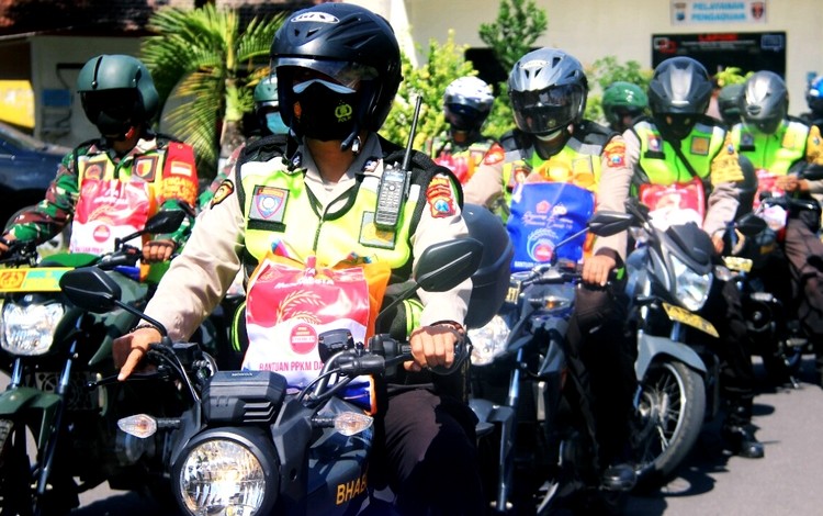 Anggota TNI-Polri tanpa kenal lelah dan waktu terus membagikan bantuan sembako pada warga terdampak PPKM Darurat Covid-19 di seluruh desa di Bondowoso. (foto: Guido/Ngopibareng.id)