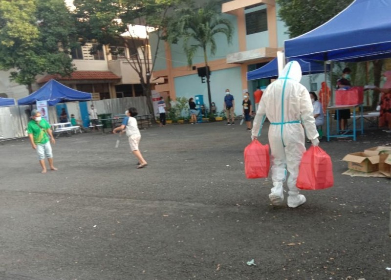 Tim Trenggana Satpol PP Jatim mengenakan APD saat mengimkan nasi kotak untuk makan pagi pasien Covid-19 di gedung E2 Asrama Haji Sukolilo Surabaya. (Foto: Kominfo Jatim)