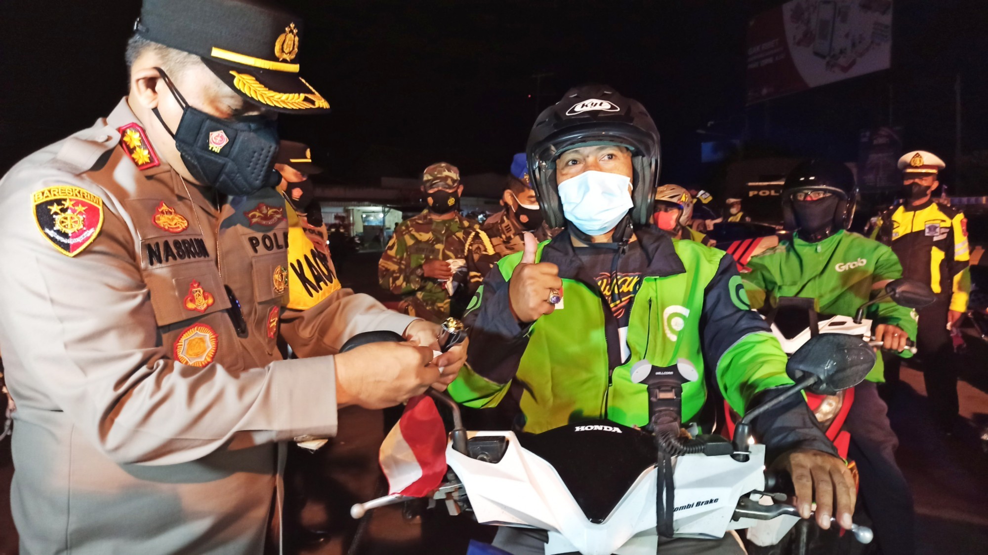 Kapolresta Banyuwangi AKBP Nasrun Pasaribu memasangkan bendera pada spion motor seorang pengendara ojek online (foto:Muh Hujaini/Ngopibaren.id)