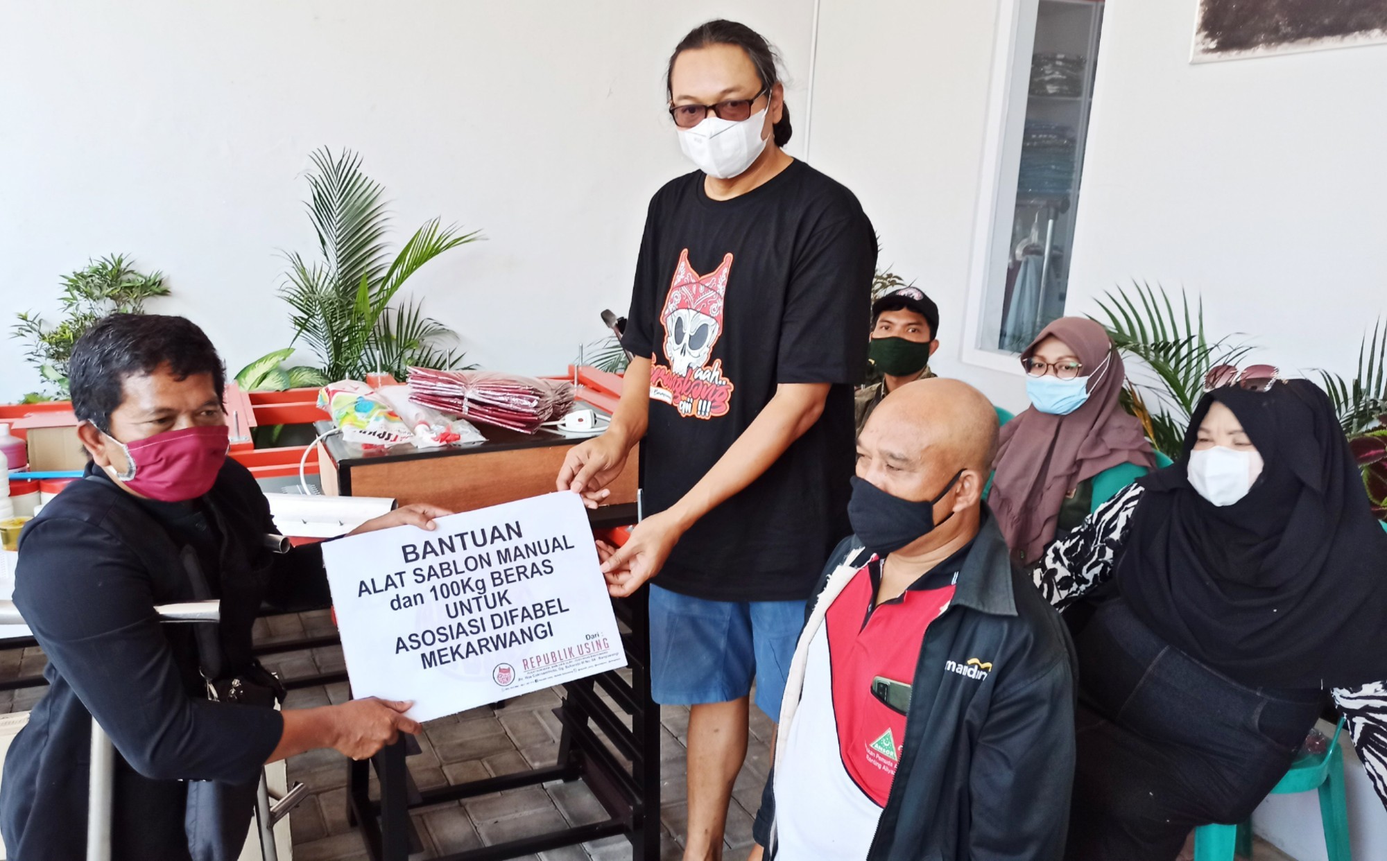 Pram (kanan) menyerahkan satu set peralatan sablon pada ketua komunitas difabel Mekarwangi. (Foto: Muh Hujaini/Ngopibareng.id)