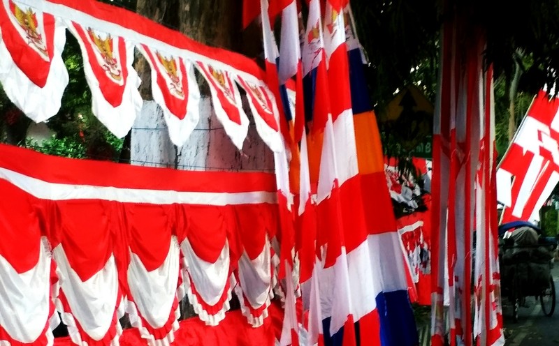 Mendekati peringatan HUT ke-75 Kemerdekaan RI 2021, bendera merah putih dan umbul-umbul dijual penjual musiman di pinggir jalan kota Bondowoso banyak belum laku terjual. (Foto: Guido Saphan/Ngopibareng.id)