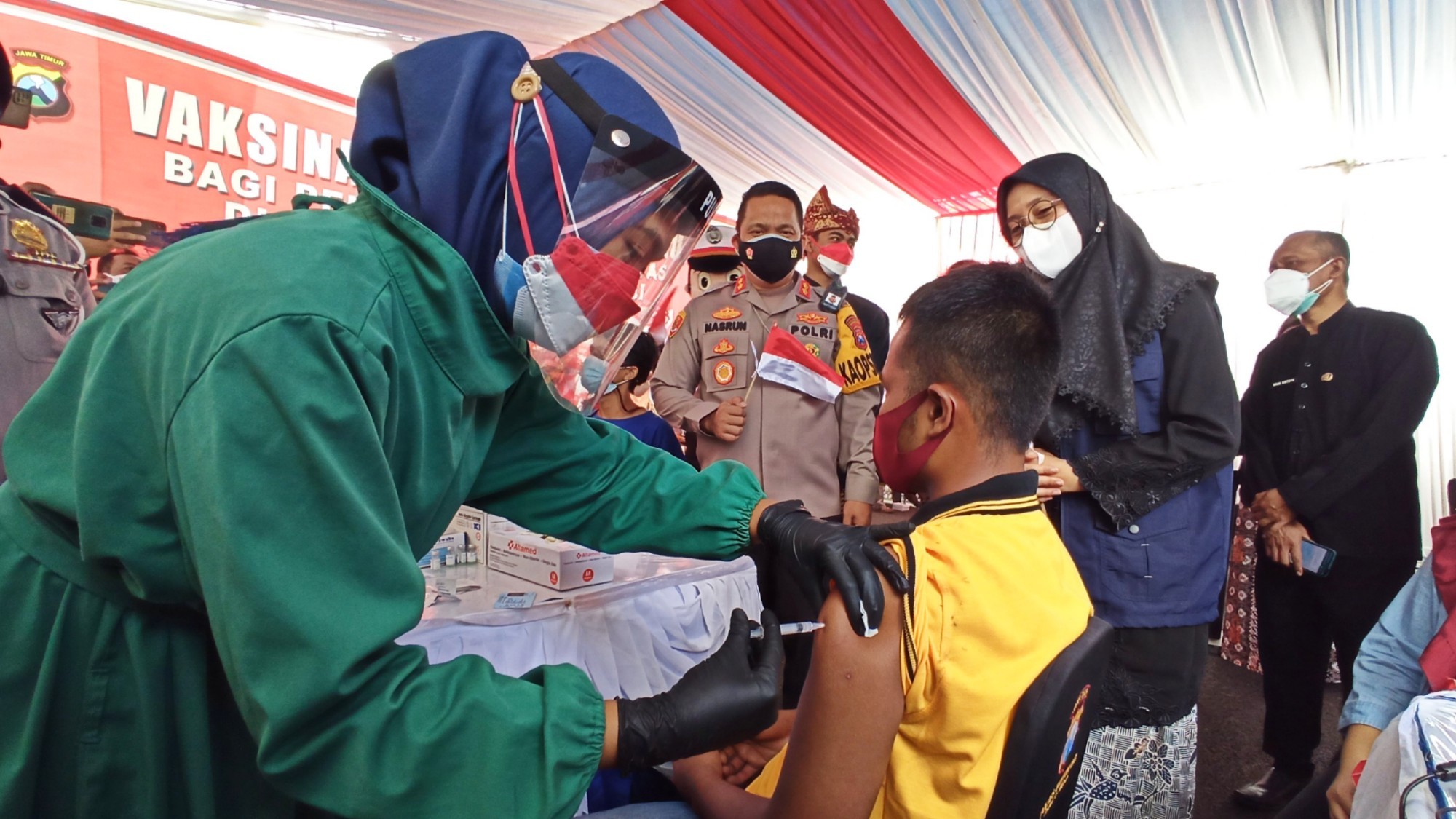 Salah seorang difabel menerima suntikan vaksin covid-19 sinopharm disaksikan Bupati Banyuwangi Ipuk Fiestiandani dan Kapolresta Banyuwangi AKBP Nasrun Pasaribu (foto:Muh Hujaini/Ngopibareng.id)