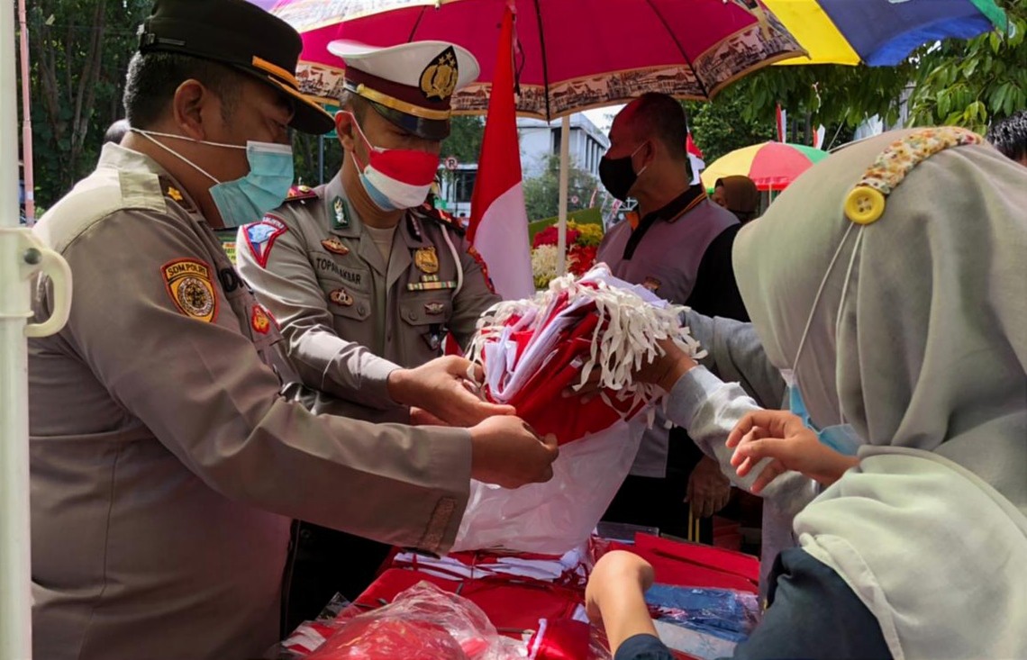 Kabag Sumda Polresta Banyuwangi, Kompol Idham Kholid memborong bendera merah putih dari salah satu pedagang kaki lima (PKL) untuk dibagikan ke warga. (Foto: Istimewa)