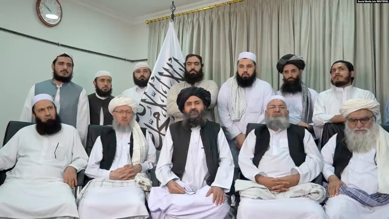 Mullah Baradar Akhund, seorang pejabat senior Taliban, duduk bersama sekelompok pria, membuat pernyataan video, dirilis pada 16 Agustus 2021. (Foto: Medsos-reuters)