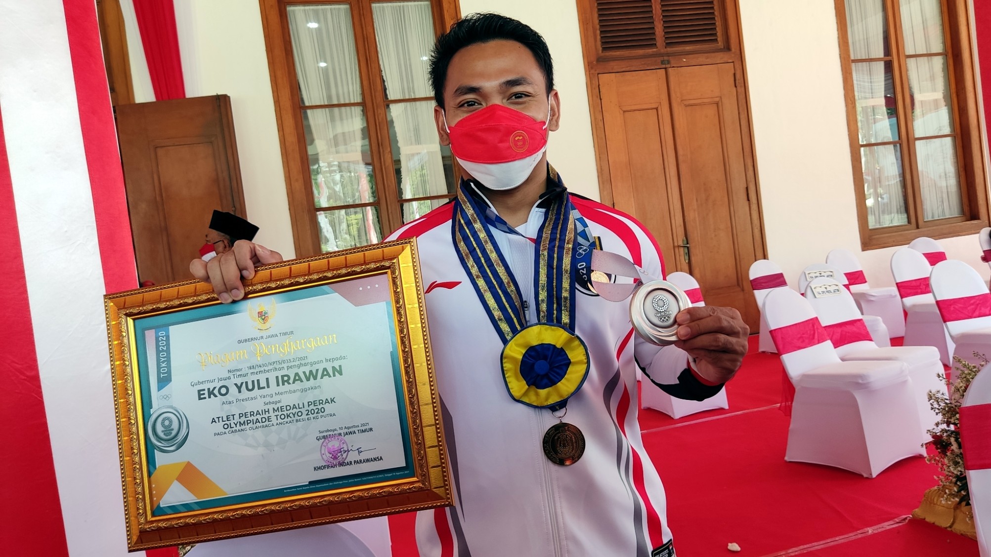 Atlet peraih medali perak Olimpiade Tokyo 2020, Eko Yuli Irawan menunjukkan medali dan penghargaan yang diterima dari Gubernur Jatim, Khofifah Indar Parawansa di Gedung Negara Grahadi, Surabaya, Selasa 17 Agustus 2021. (Foto: Fariz Yarbo/Ngopibareng.id)