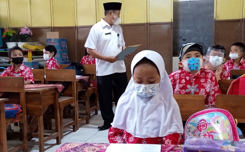 Kepala SDN Kota Kulon 1 Liwon memantau siswa yang antusias belajar memakai masker dan menjaga jarak. (Foto: Guido Saphan/Ngopibareng.id)