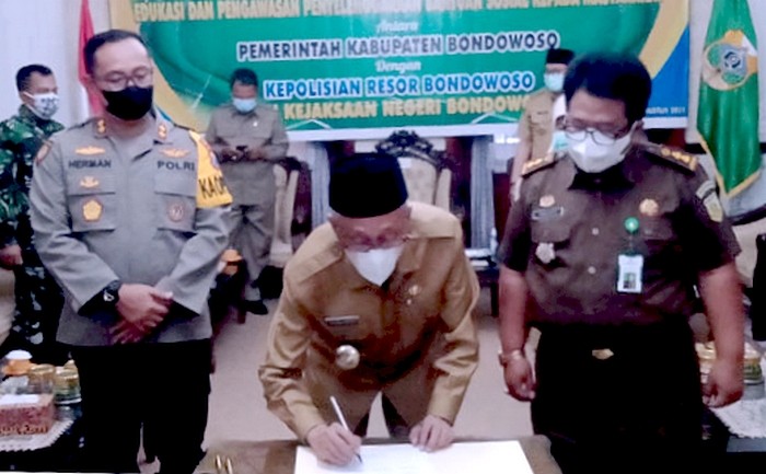 Bupati Bondowoso Salwa Arifin menandatangi nota kesepahamanan pengawasan penyaluran bansos kepada masyarakat disaksikan Kapolres AKBP Herman Priyanto dan Kasi Intel Kejari setempat Sucipto, Senin 23 Agustus 2021. (Foto: Guido Saphan/Ngopibareng.id)