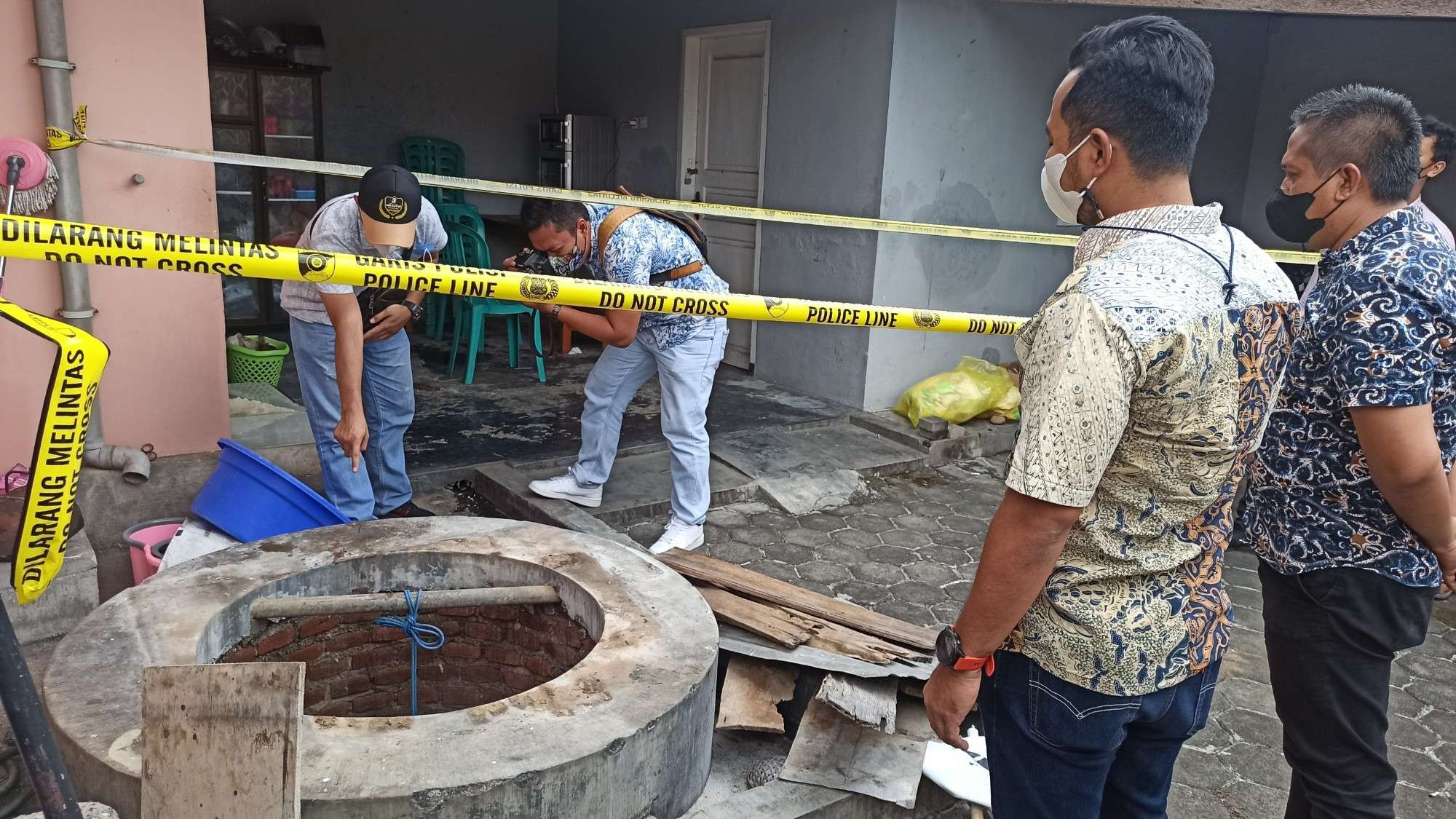 Petugas Kepolisian melakukan olah TKP di sekitar sumur yang diduga menjadi tempat dibuangnya bayi (foto:Muh Hujaini/Ngopibareng.id)