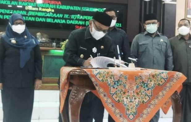 Bupati Situbondo Karna Suswandi menandatangani Perda P-APBD 2021 yang dsahkan DPRD dalam paripurna di gedung DPRD Situbondo, Senin 27 September 2021 malam. (Foto: Istimewa)