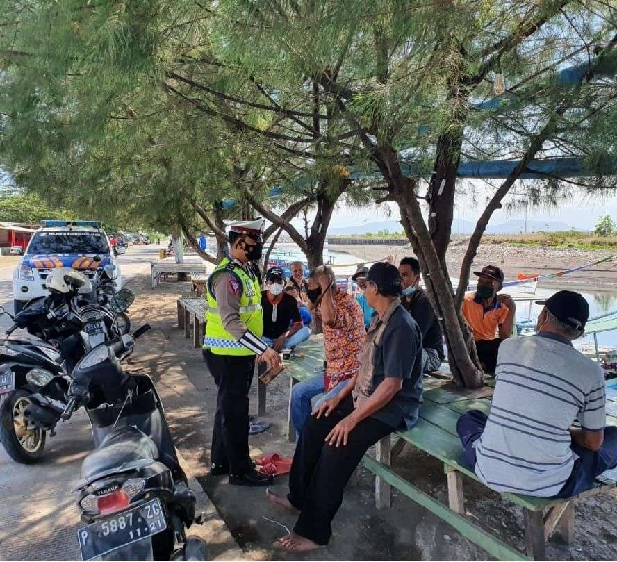 Petugas Polantas membagikan masker pada warga yang kedapatan tidak menggunakan masker di kawasan wisata kuliner plengsengan, Banyuwangi (foto:istimewa)