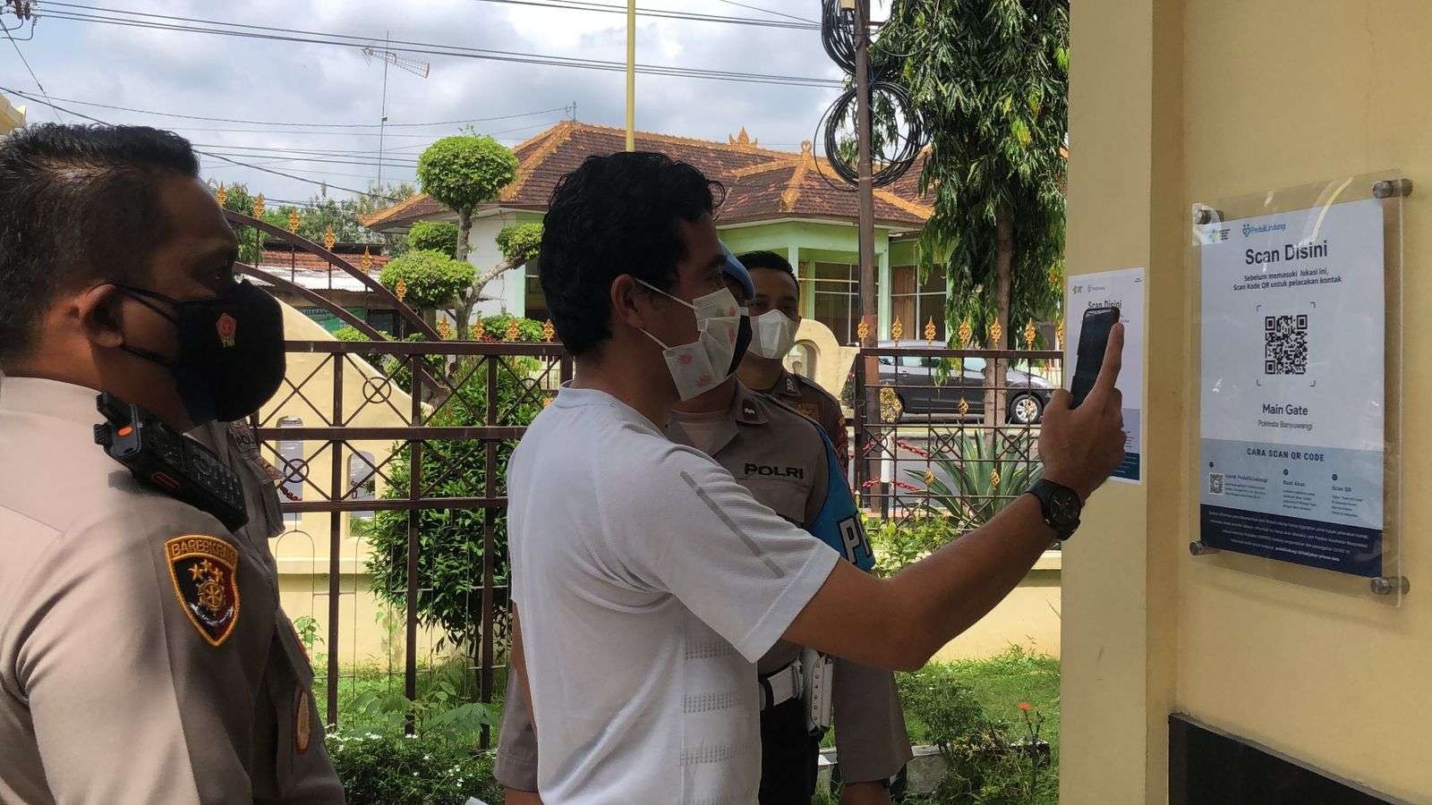 Kapolresta Banyuwangi AKBP Nasrun Pasaribu melihat salah seorang pengunjung Polresta Banyuwangi sedang check ini dengan melakukan scan QR code melalui aplikasi PeduliLindungi. (Foto: Istimewa)