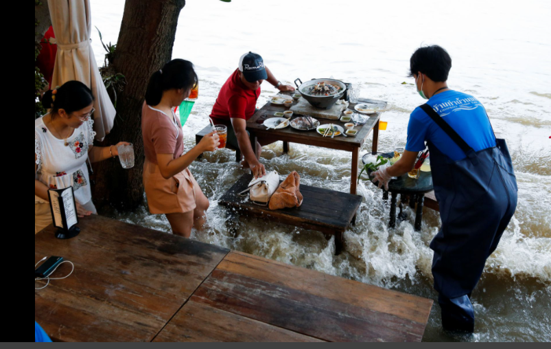 Pengusaha tetap buka di tengah gelombang ombak sungai, serta banjir. Video kafe yang buka di tengah banjir di Thailand pun viral. (Foto: Reuters)