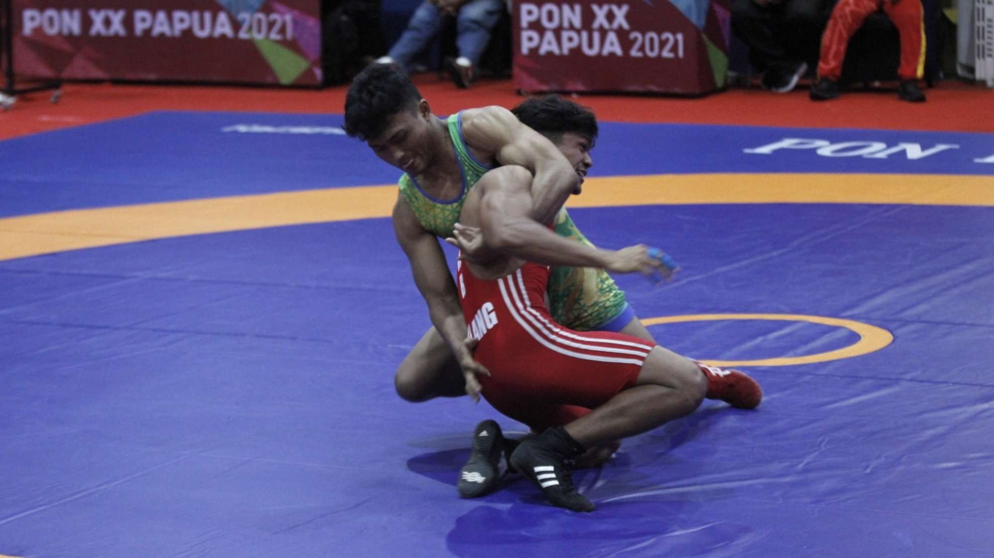 Pegulat Jatim, Rachmat Hadi (hijau) berusaha membanting Pegulat Sumbar Gilang Ilhasa di babak final kelas 74 Kg di GOR Futsal Dispora, Merauke, Senin 11 Oktober 2021. (Foto: Fariz Yarbo/Ngopibareng.id)