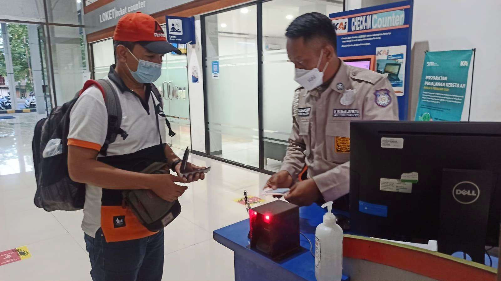 Petugas Stasiun sedang memeriksa identitas dan tiket salah satu calon penumpang KA di Stasiun Ketapang, Banyuwangi (foto: Muh Hujaini/Ngopibareng.id)