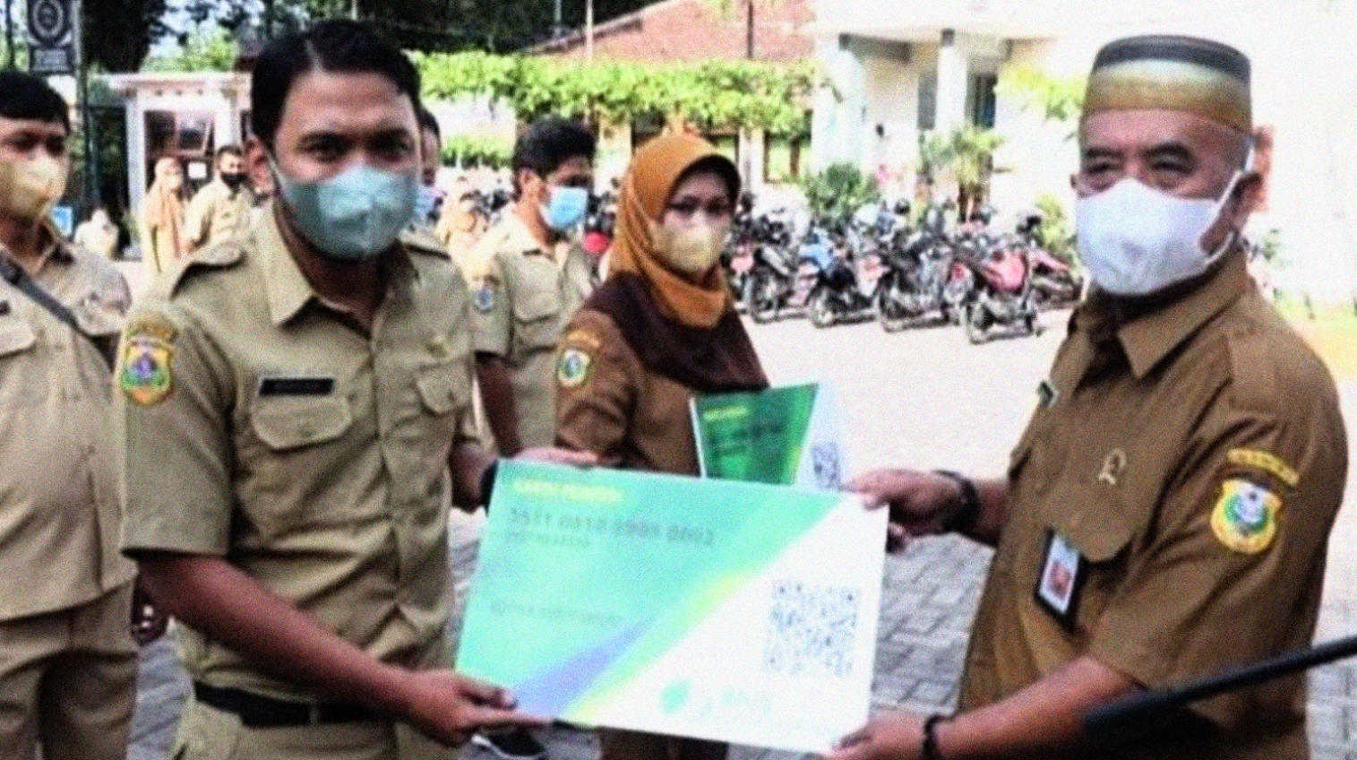 Kepala Dinas Pendidikan dan Kebudayaan Bondowoso Sugiono Eksantoso menyerahkan kartu peserta BPJS Ketenagakerjaan kepada perwakilan PTT. (Foto: Guido Saphan/Ngopibareng.id).