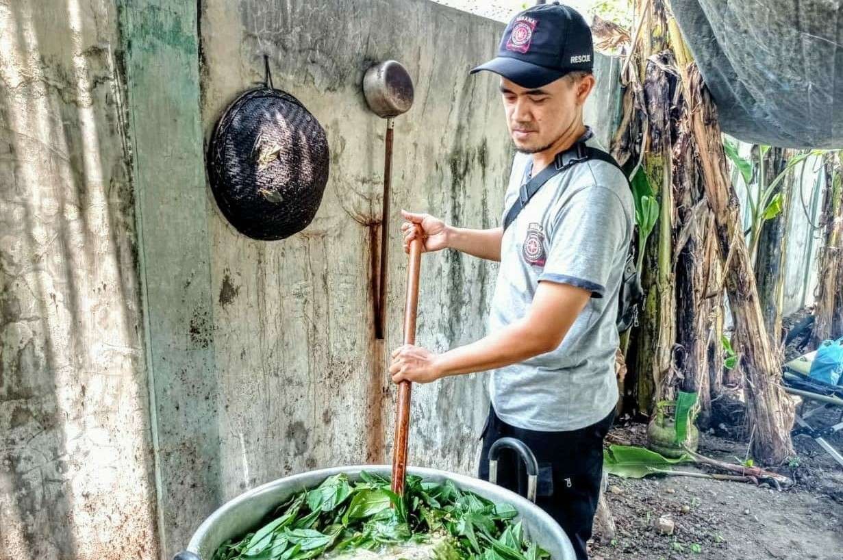 Hariyanto, salah seorang relawan taruna tanggap bencana (TAGANA) Kabupaten Jombang saat mengaduk panci berisi 200 liter air jamu penangkal covid di dapur umur Dinas Sosial pada Minggu, 31 Oktober 2021. Jamu ini terbuat dari campuran daun dan rempah tradisional yang telah dicuci dan dihaluskan. (Foto: Mutqiyyah Rizqi/Ngopibareng.id)