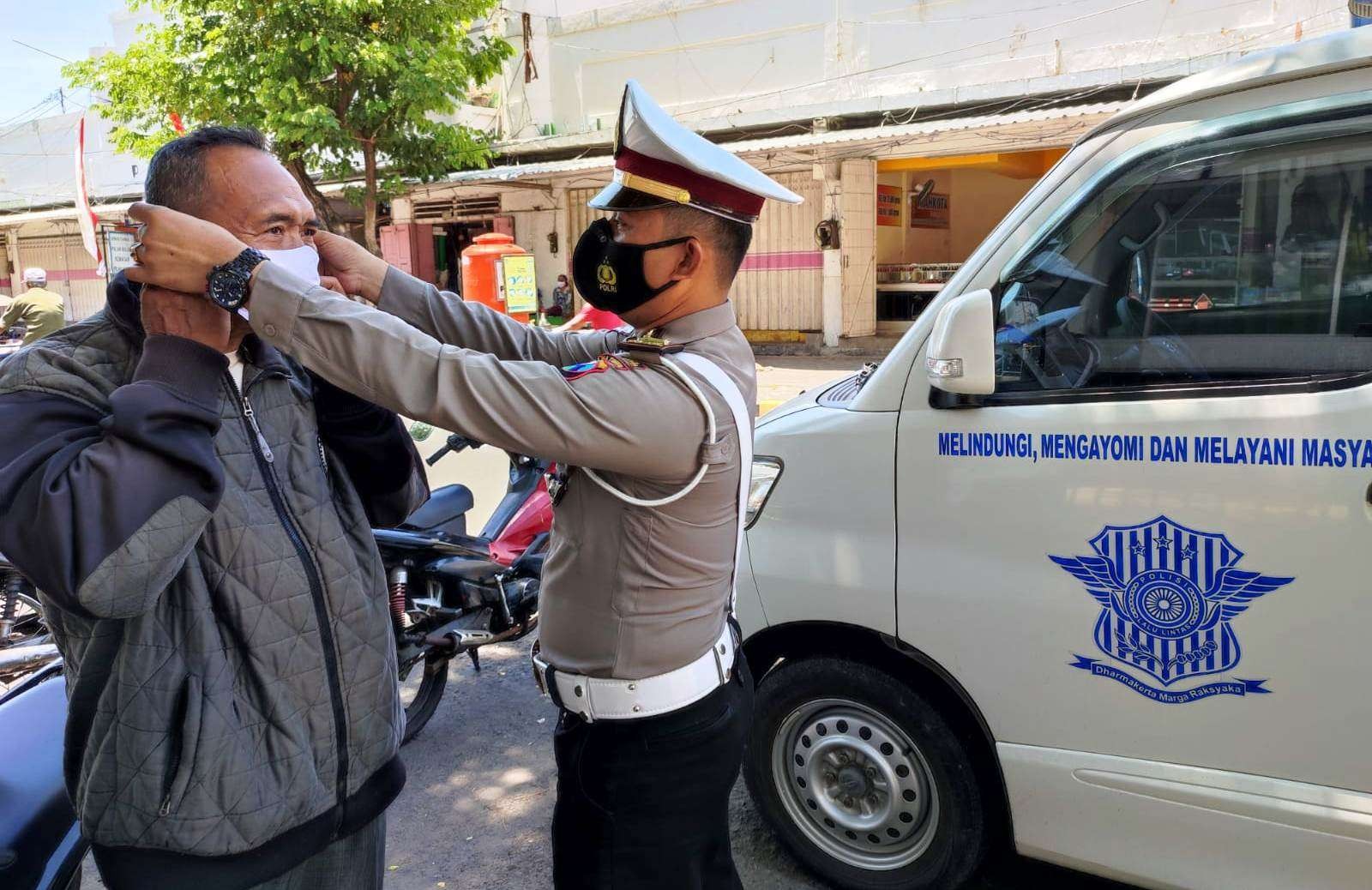 Petugas Satlantas Polresta Banyuwangi memasangkan masker kepada warga yang kedapatan tidak menggunakan masker. (Foto: Istimewa)