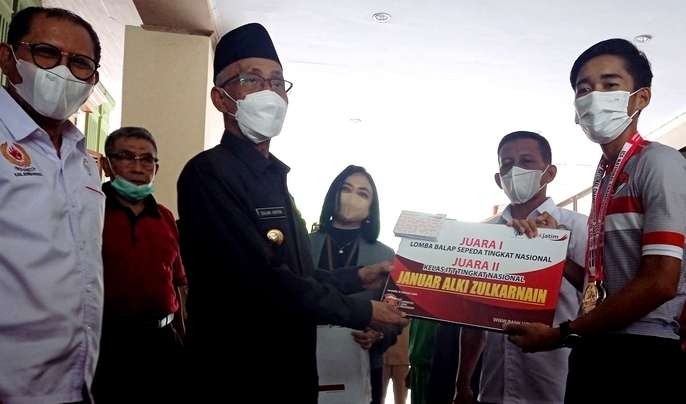 Yanuar Alqi Zulkarnaen mewakili tim balap sepeda Bondowoso peraih medali emas dan perak Kejurnas Balap Sepeda 2021 di Garut-Cimahi, 22-27 Oktober 2021, menerima bonus tabungan  yang diserahkan Bupati KH. Salwa Arifin. (Foto: Guido/ngopibareng.id)