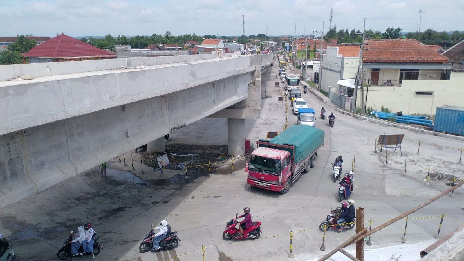 Pemandangan padatnya arus lalu lintas di Simpang Tiga Ploso dari atas jembatan baru yang masih dibangun. Ruas jalan ini menjadi titik bertemunya kendaraan dari berbagai arah yaitu Jombang, Mojokerto, Lamongan, dan Nganjuk. (Foto: Mardiansyah Triraharjo/Ngopibareng.id)