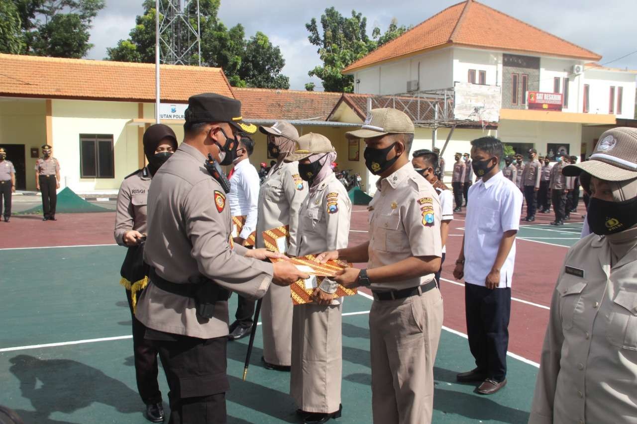 Kapolres AKBP Herman Priyanto menyerahkan penghargaan berprestasi pelayanan publik kepada 12 anggota Polres Bondowoso atas terobosan inovasi dan dedikasinya. (Foto:Guido Saphan/Ngopibareng.id)