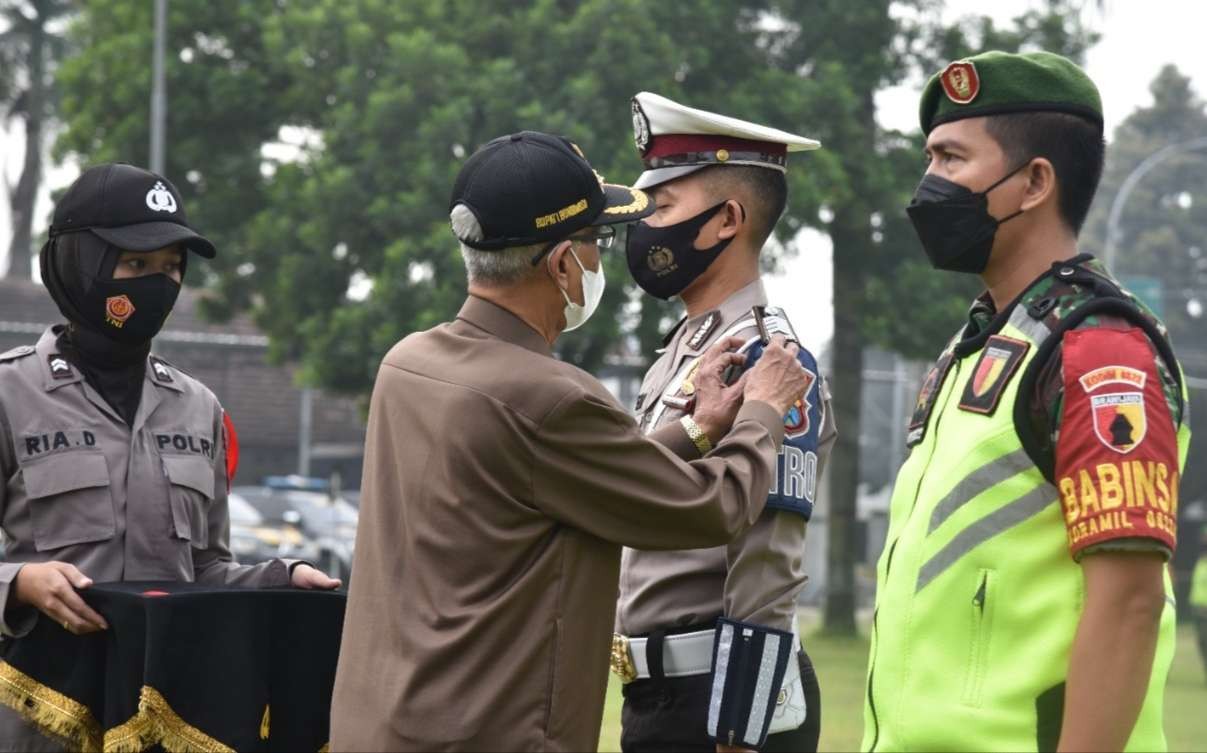 Bupati Bondowoso KH Salwa Arifin memasang pita kepada petugas pengamanan Operasi Lilin Semeru 2021 secara simbolis.(Foto: Guido/ngopibareng.id)