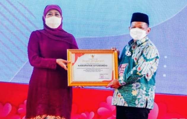 Gubernur Jatim Khofifah Indar Parawansa menyerahkan penghargaan responsif layanan perempuan dan anak kepada Bupati Situbondo Karna Suswandi(foto:diskominfodan situbondo).