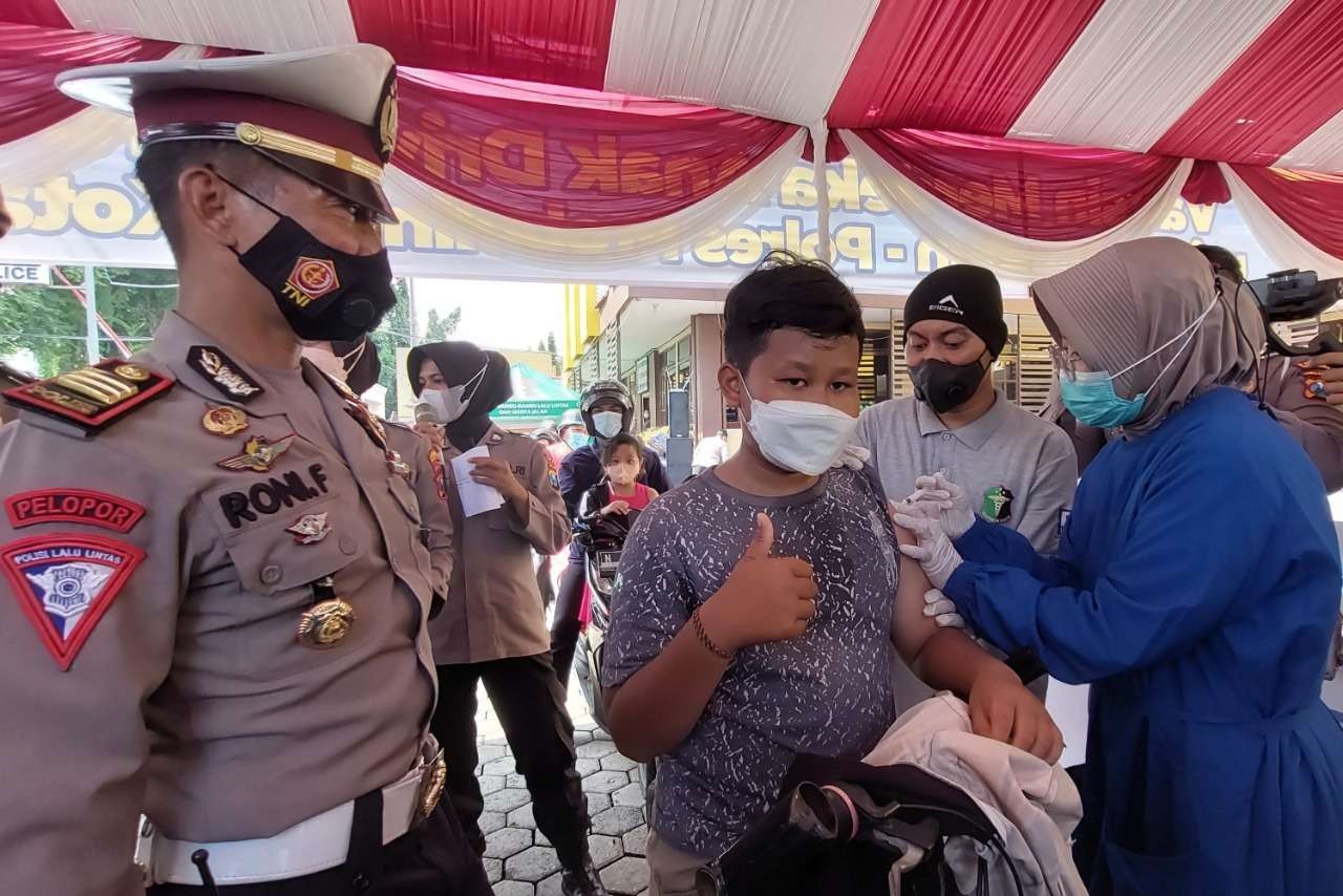 Seorang bocah nangkring di atas motornya divaksin di halaman Mapolresta Probolinggo. (Foto: Ikhsan Mahmudi/Ngopibareng.id)