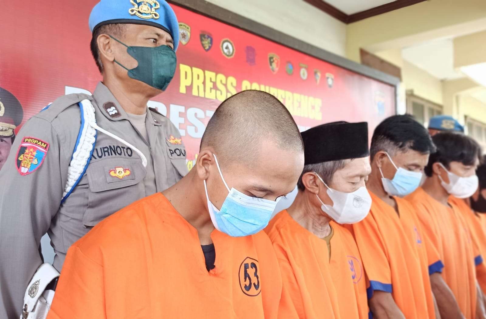 Tersangka kasus sodomi memakai baju tahanan nomor dada 53. Pria berkepala plontos ini tertunduk saat Polresta Banyuwangi melakukan rilis kasus pada Kamis, 13 Januari 2022 pagi. (Foto: Muh Hujaini/Ngopibareng.id)