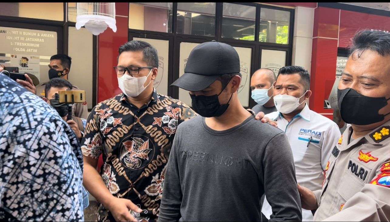 Tersangka penendang sesajen, Hadfana Firdaus (topi hitam) saat diamankan aparat di Mapolda Jatim, Surabaya, Jumat 14 Januari 2021. (Foto: Fariz Yarbo/Ngopibareng.id)