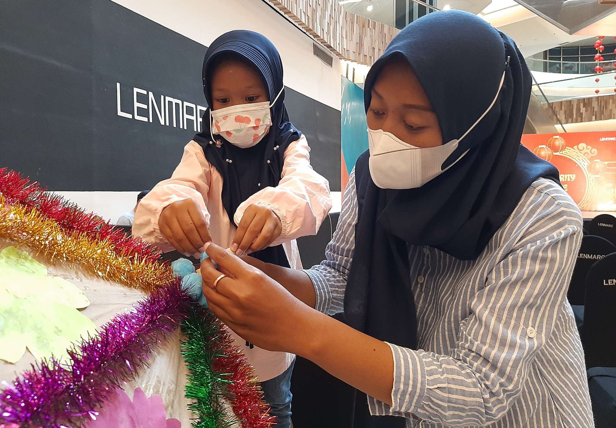 Pasangan ibu dan anak, Mia dan Kaia saat menghias payung menyambut Imlek. (Foto: Pita Sari/Ngopibareng.id)