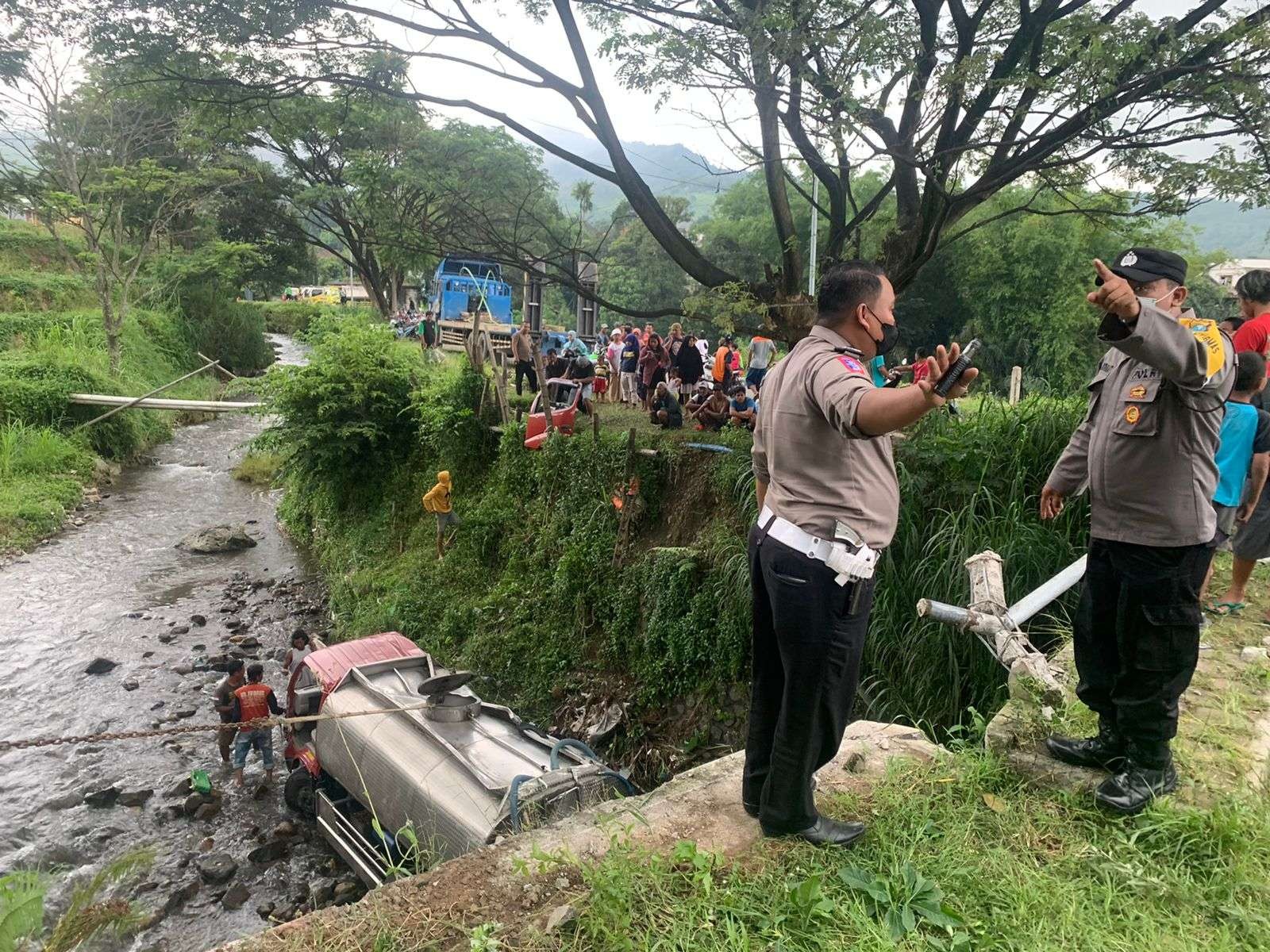 Polisi dibantu relawan mengevakuasi truk tangki air dari sungai. (Foto: Deni Lukmantara/Ngopibareng.id)