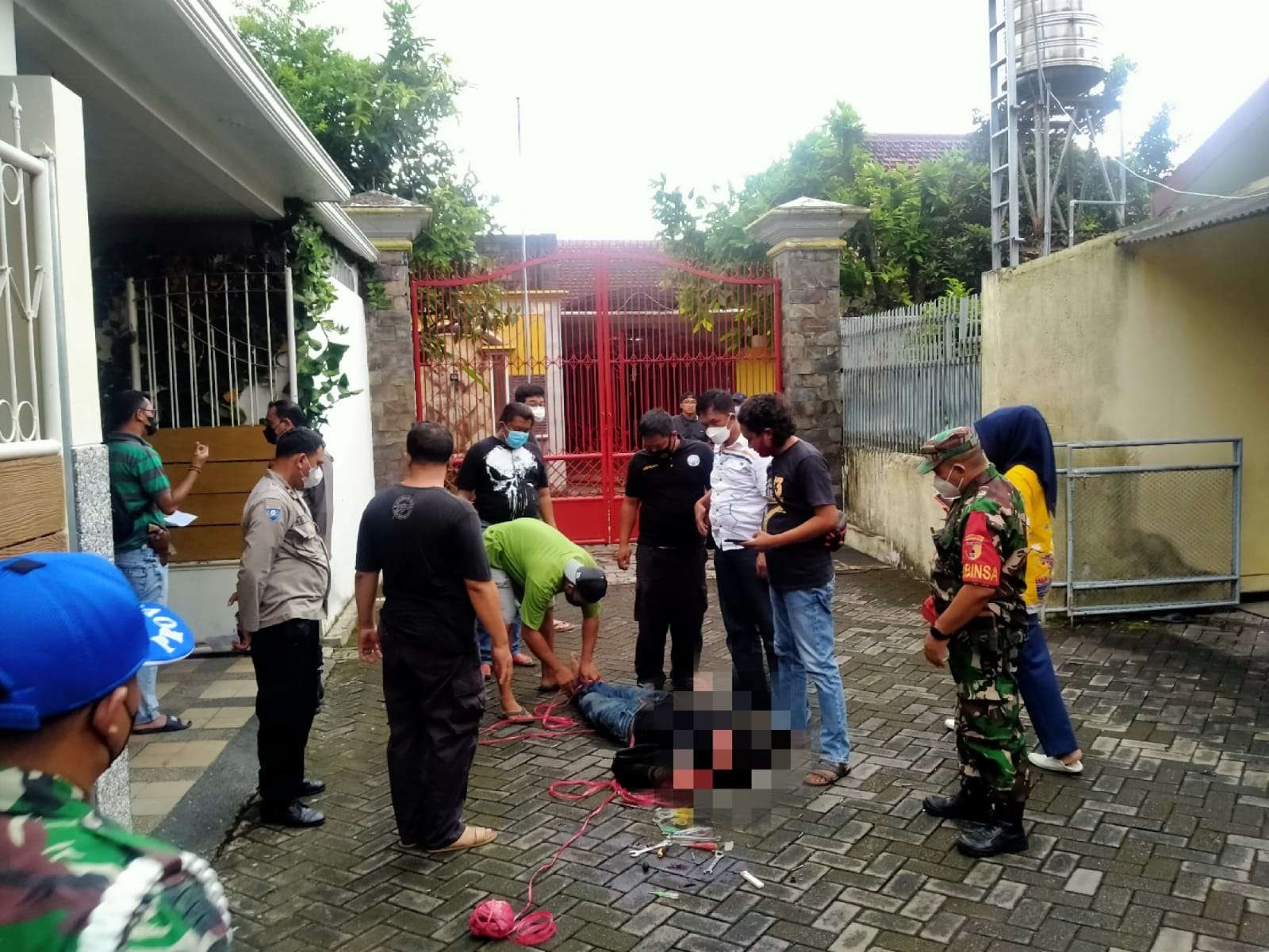 Polisi melepas ikatan di tubuh pelaku yang terkapar sebelum dibawa ke rumah sakit. (Foto:Rusdi/Ngopibareng.id)