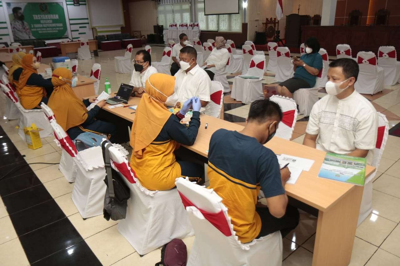 Kepala-kepala perangkat daerah di Kota Probolinggo mengikuti vaksinasi booster di Puri Manggala Bhakti. (Foto: Ikhsan Mahmudi/Ngopireng.id) ----------  Para Kepala Perangkat Daerah Disuntik Vaksin Booster   Ngopibareng.id | Vaksin ketiga atau booster mulai digencarkan di Kota Probolinggo. Selain melayani vaksin pada fasilitas kesehatan (Puskesmas), petugas juga jemput bola ke sejumlah kelurahan hingga perkantoran di lingkungan Pemerintah Kota (Pemkot) Probolinggo.  Para kepala perangkat daerah di lingkungan Pemkot Probolinggo misalnya, menjalani vaksinasi booster di Puri Manggala Bhakti pemkot setempat, Jumat, 4 Februari 2022.  “Syukurlah, masyarakat sangat baik responya terhadap vaksin booster. Saya meyakini, banyak warga yang menunggu vaksin dosis ketiga ini,” kata dr Santy dari Puskesmas Kanigaran di sela-sela vaksinasi booster, Jumat.  Sisi lain, sejumlah warga usai divaksin mengaku, nyeri di bagian lengan yang disuntik, badan sedikit meriang (demam), hingga nyeri otot dan sendi. Karena itu, kata dr Santy, disediakan kaplet paracetamol 500 miligram bagi penerima vaksin booster untuk mengantisipasi gejala tersebut.  Sejumlah kepala perangkat daerah di lingkungan Pemkot Probolinggo mengaku, menyambut baik vaksinasi dosis ketiga itu. “Demi menghadapi Covid-19 variasi baru, Omicron maka kita perlu vaksin booster,” ujar Kepala Dinas Satpol PP, Linmas, dan Damkar, Aman Suryaman.  Mantan Kadis Kominfo itu mengaku, melakukan sejumlah persiapan untuk mengurangi efek samping usai vaksin booster di antaraya, istirahat cukup dan sarapan lebih dulu.   “Alhamdulillah, tadi saya sudah divaksin, setelah menunggu 10 menit tidak  ada reaksi apa pun. Jangan takut untuk divaksin booster,” ujarnya.  Sementara berdasarkan data Dinkes P2KB, capaian vaksinasi Covid-19 di Kota Probolinggo per tanggal 3 Februari 2022 menunjukkan total sasaran vaksin pertama sebanyak 86,39 persen, sedangkan vaksin kedua mencapai 70,94 persen.   Sementara itu, untuk vaksin anak tahap pertama mencapai 80,80 persen. Untuk vaksin ketiga (booster) masih 4,65 persen. (Foto: Ikhsan Mahmudi/Ngopibareng.id)