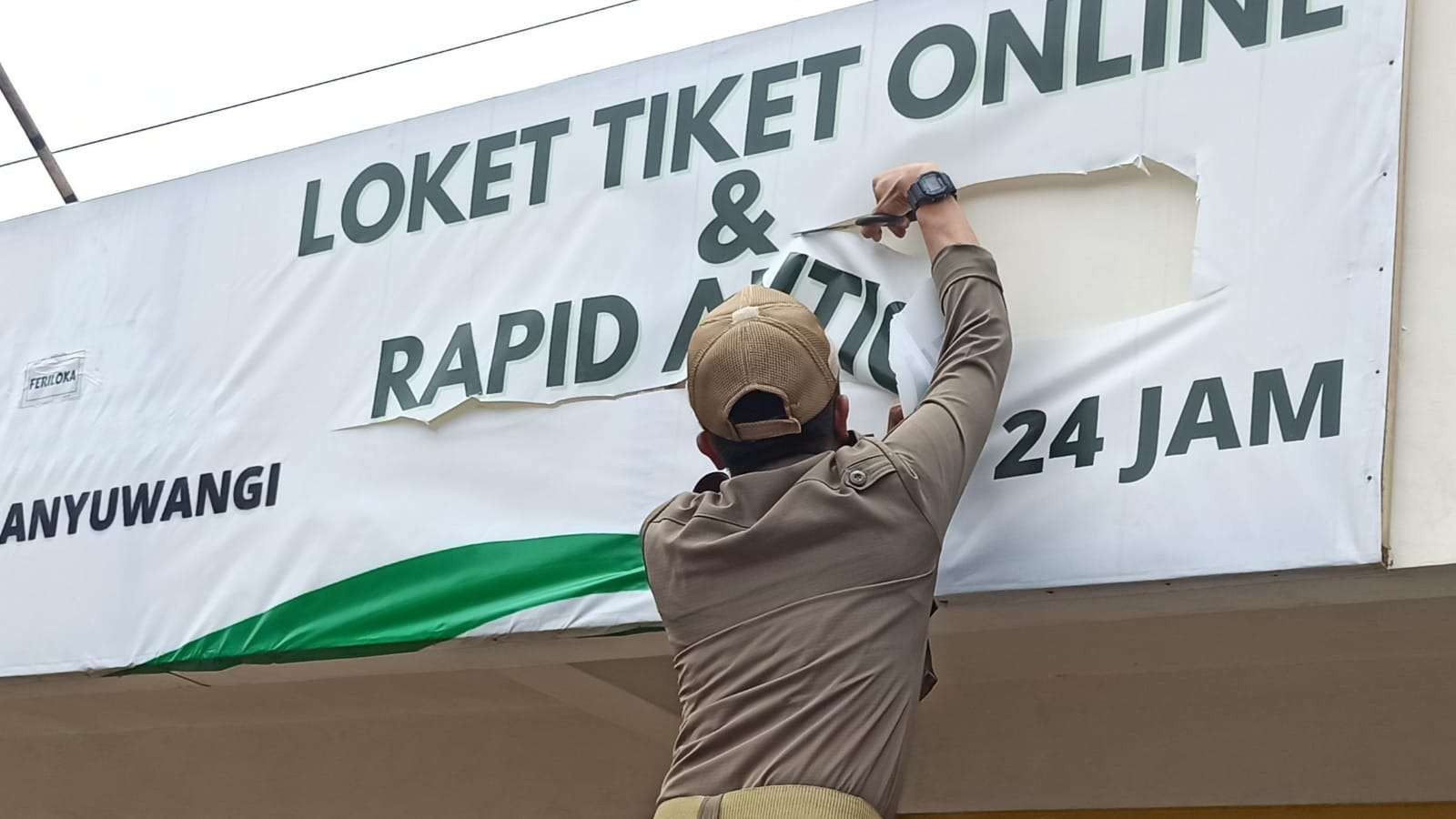 Petugas Satpol PP menertibkan banner salah satu fasilitas layanan rapid antigen di sekitar pelabuhan Ketapang (Foto: Muh Hujaini/Ngopibareng.id)