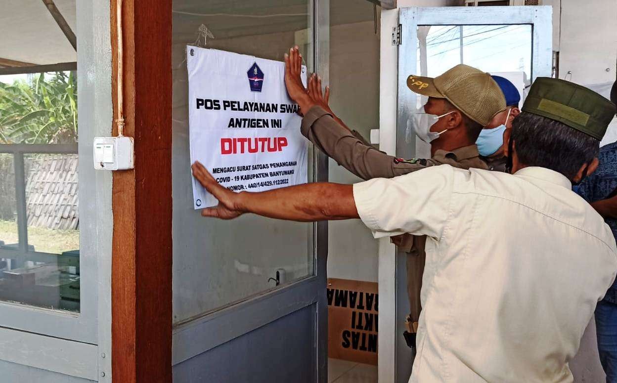 Petugas memasang segel penutupan layanan rapid antigen di salah satu layanan rapid antigen di sekitar Pelabuhan Ketapang, Banyuwangi (Foto: Muh Hujaini/Ngopibareng.id)