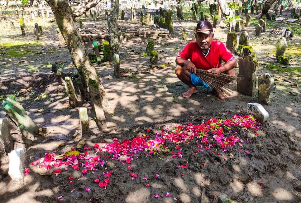 Juru kunci dan makam yang terbongkar setelah dirapikan kembali (foto:Aini/Ngopibareng.id)