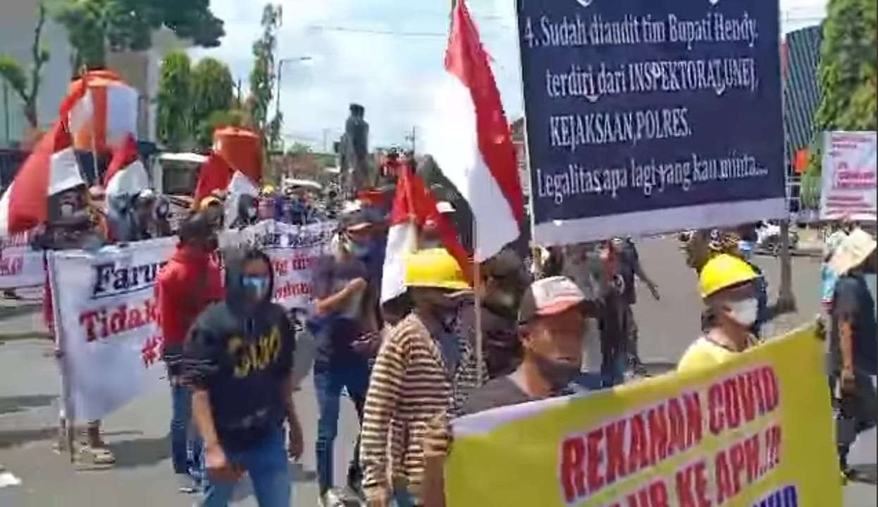 Ratusan rekanan proyek wastafel melakukan unjuk rasa sambil membentangkan sejumlah poster di Jember. (Foto: Rusdi/Ngopibareng.id)