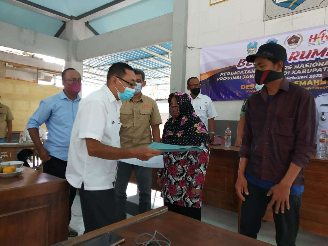 Kepala Dinas Kominfo Pemkab Lamongajln Sugeng Widodo menyerahkan SK bedah rumah kepada  keluarga Misbakhul Munir, warga Desa Dermo Lemahbang, Lamongan. (Foto: Imron Rosidi/Ngopibareng.id)