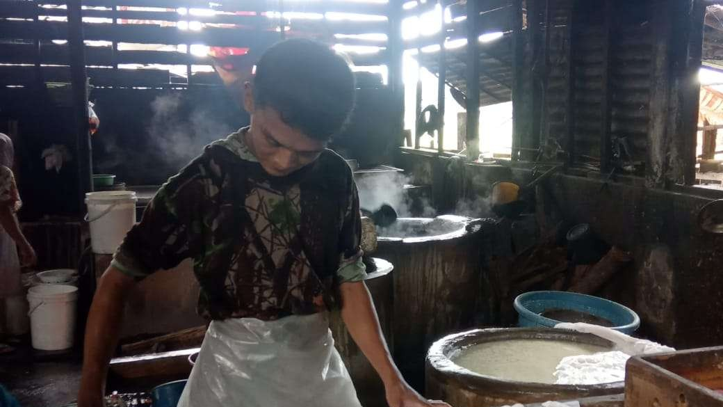 Salah seorang pengrajin tahu di Kelurahan Ledok Kulon, tengah mengukur lembaran tahu sesuai ukurannya. (Foto: Sujatmiko/Ngopibareng.id)