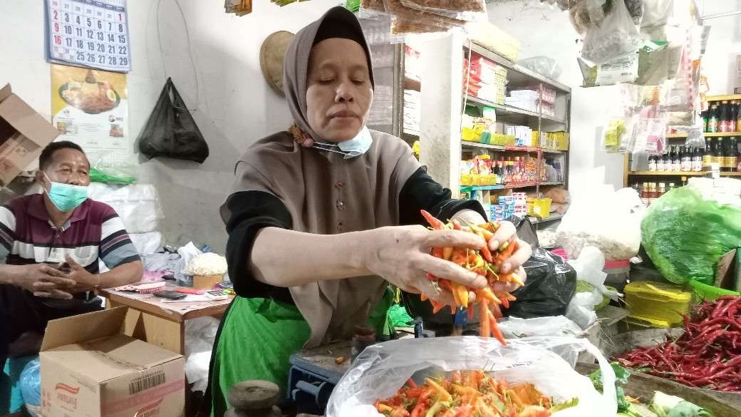 Pedagang cabai di Pasar Baru Tuban sedang memperlihatkan cabainya ke pembeli. (Foto: Khoirul Huda/Ngopibareng.id)