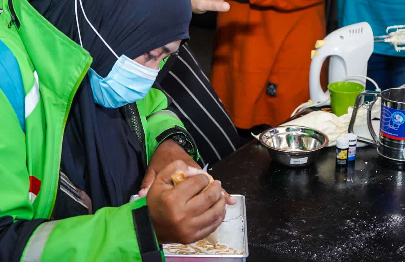 Driver ojol perempuan sedang membatik kue bolu. (Foto: Aini/Ngopibareng.id)